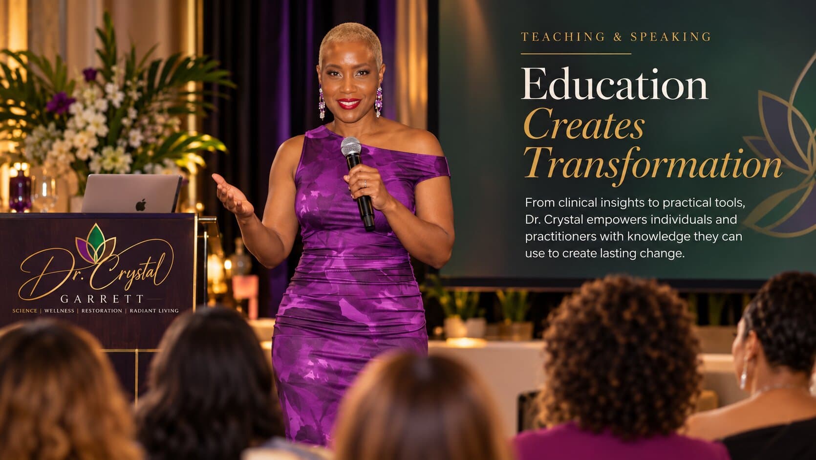 Dr. Crystal Garrett speaking to an audience from a stage, beside a screen reading Education Creates Transformation